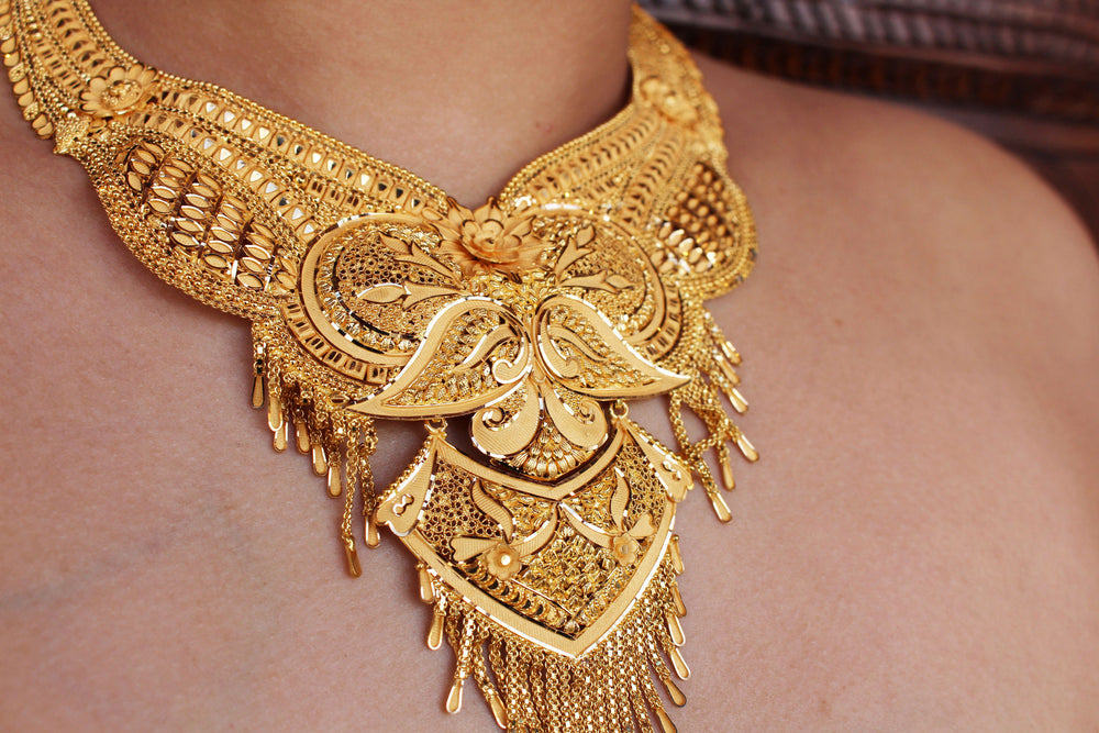 Close-up of a gold mangalsutra with intricate designs on a woman's neck.